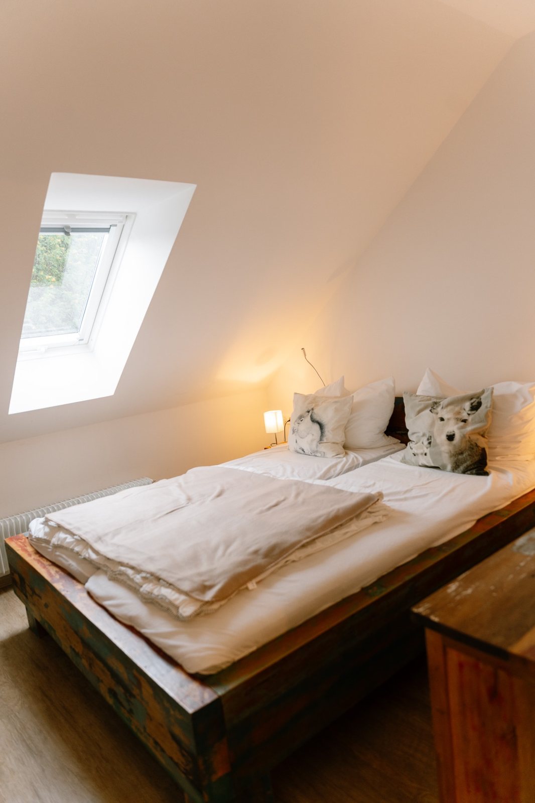 Schlafzimmer mit Doppelbett aus Holz unter der Dachschräge